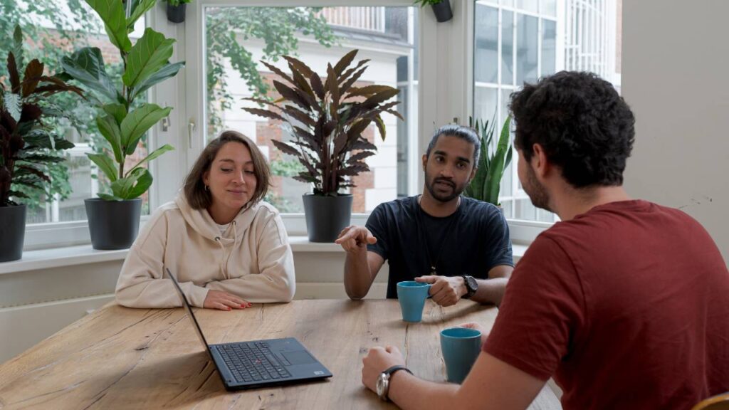 Three employees chatting in an office full of green plants